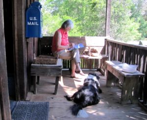 Image of a dog and a woman writing on the front deck of the Kaweah Post Office