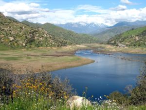 A springtime view of Lake Kaweah with snow-covered mountains in the background