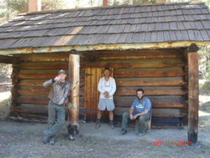 Men sitting and standing in front of the cabin