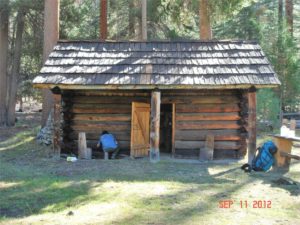 Image of front of cabin with a person working on restoration